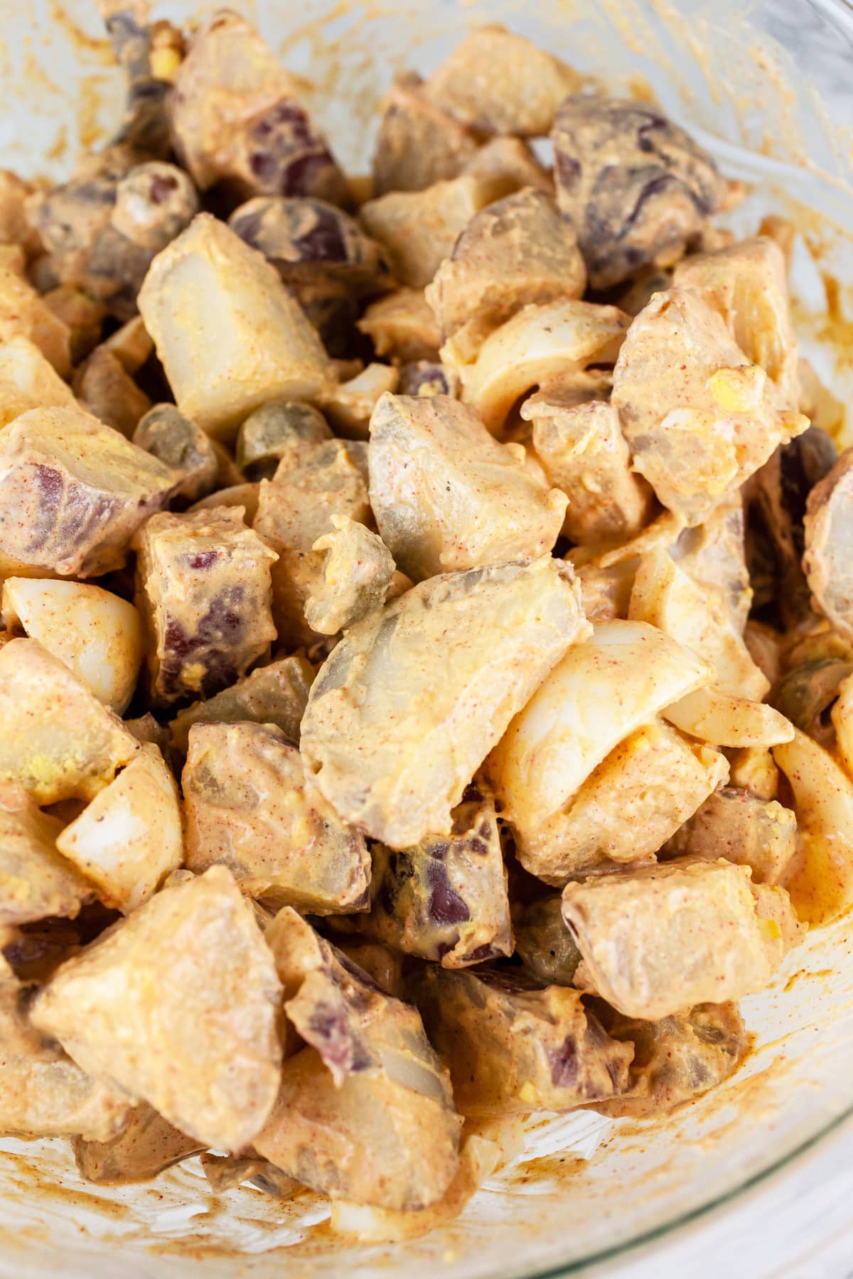 Spanish potato salad mixed together in large glass bowl.