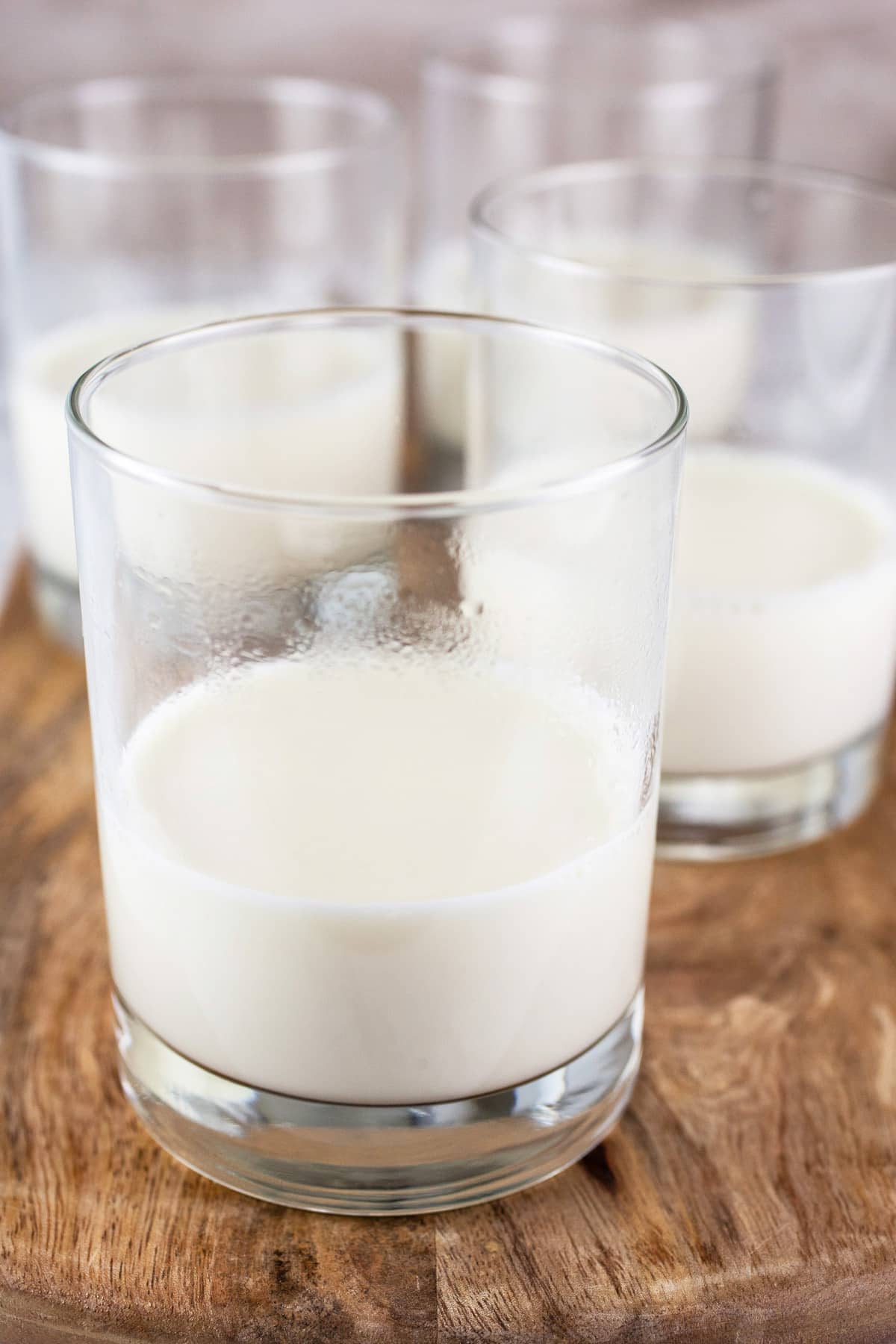 Small glasses with panna cotta mixture on wooden surface.