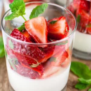 Strawberry mint panna cotta in glasses on wooden board.