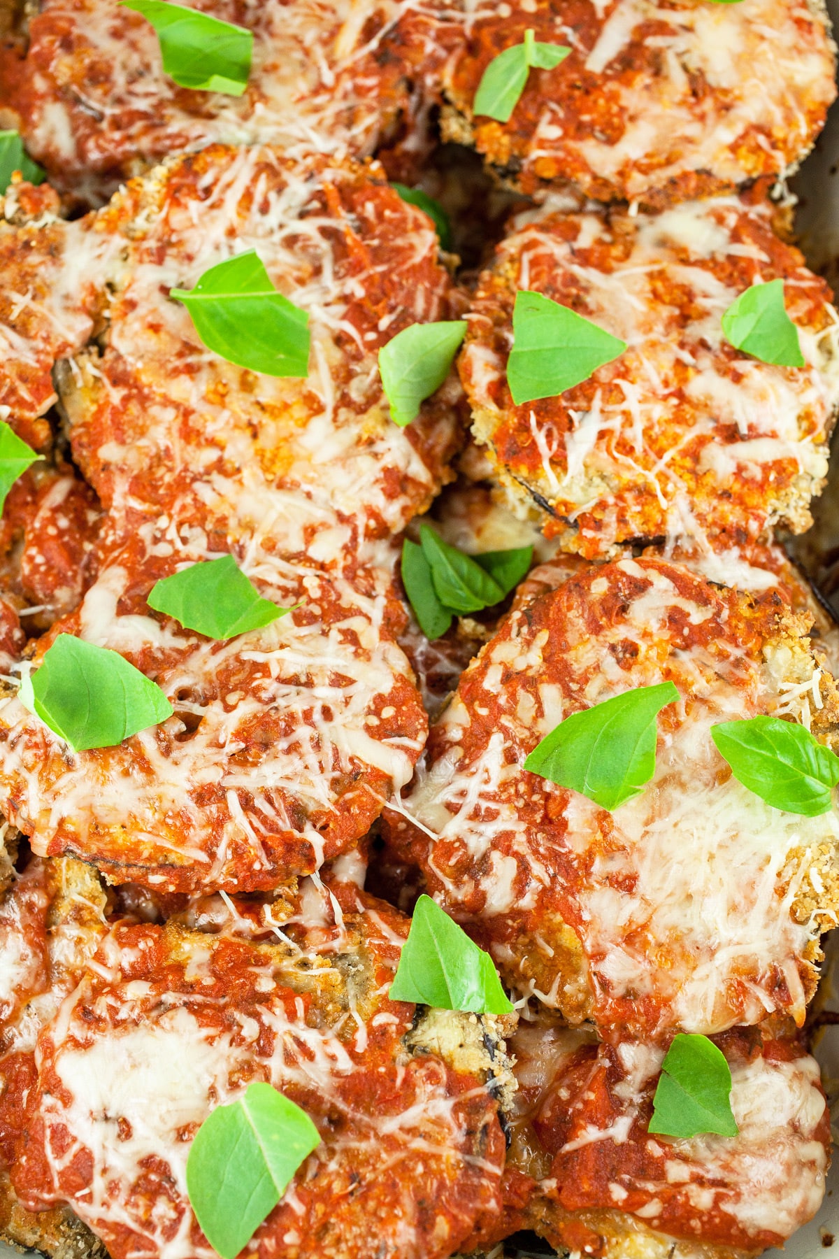 Baked eggplant parmesan with basil leaves.