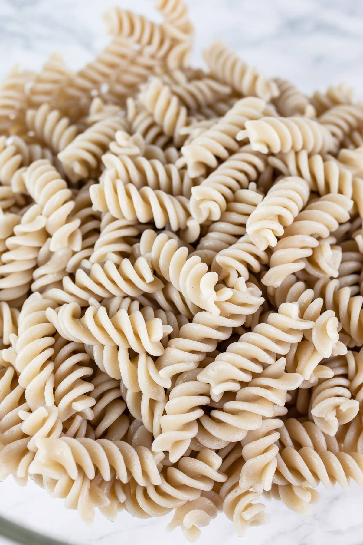 Cooked gluten free fusilli pasta in large glass bowl.