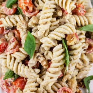 Pesto pasta salad with tomatoes and fresh basil.