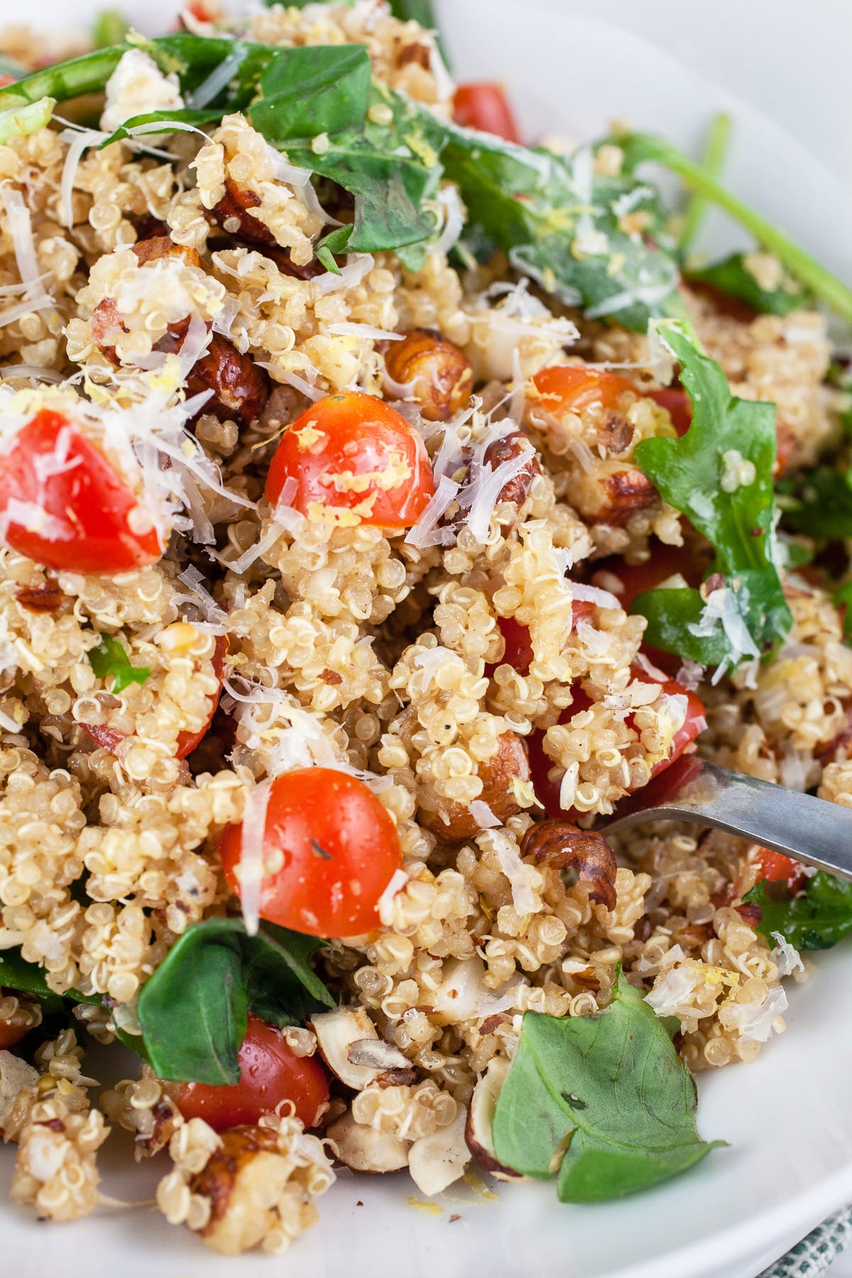 Italian quinoa salad with arugula, tomatoes, and Parmesan in white bowl.