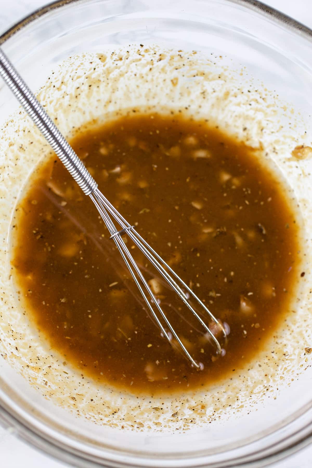 Balsamic vinaigrette in glass bowl with small whisk.