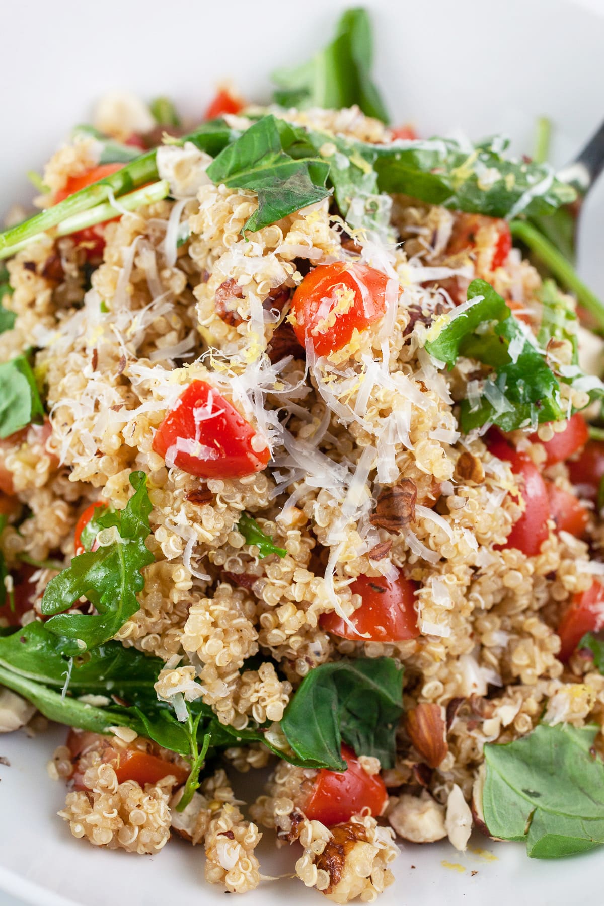 Italian quinoa salad in white bowl with fork.