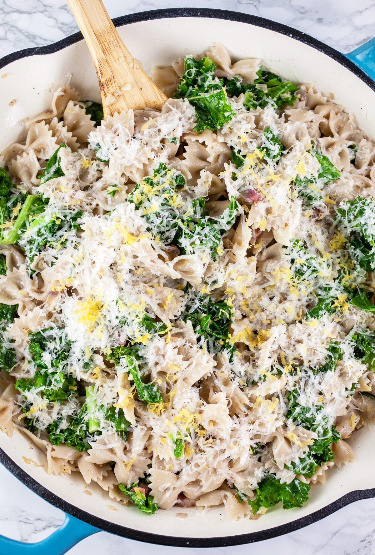 Pancetta kale pasta with shredded Asiago cheese and lemon zest in large skillet.