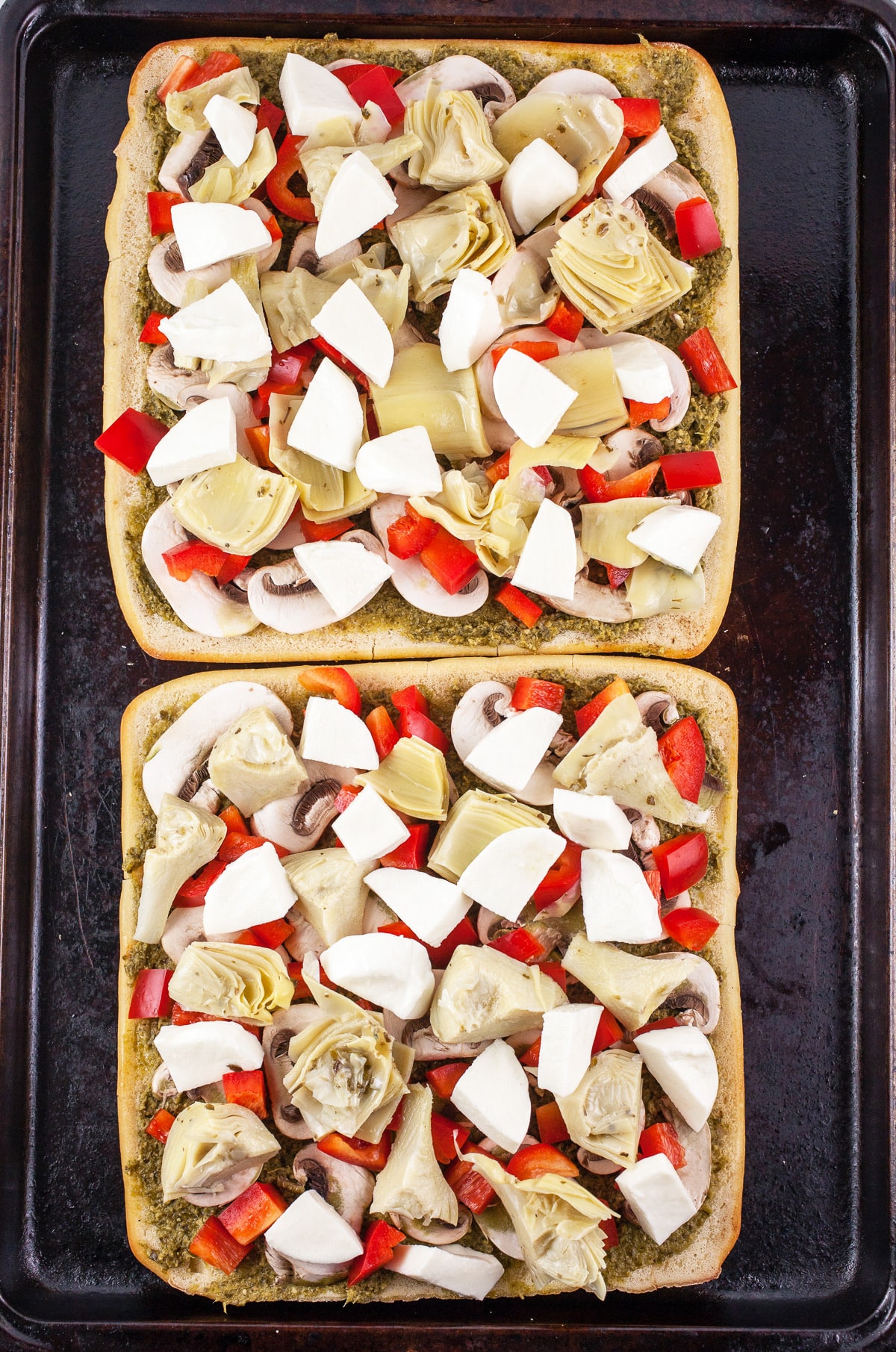 Uncooked Mediterranean flatbreads on baking sheet.