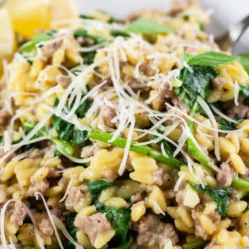 Ground turkey spinach orzo pasta with Parmesan cheese and lemon in white bowl.