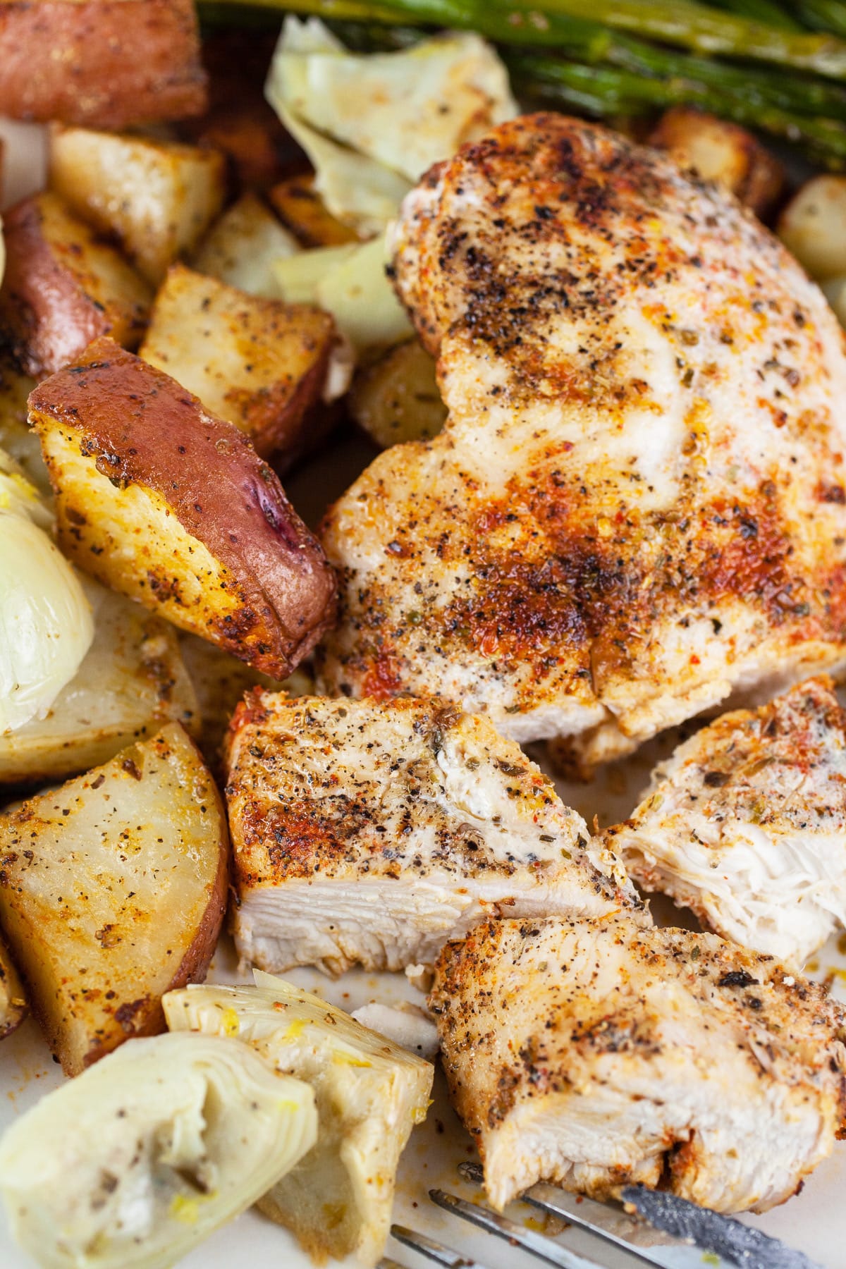 Sheet pan Mediterranean chicken and potatoes with artichokes and roasted asparagus.