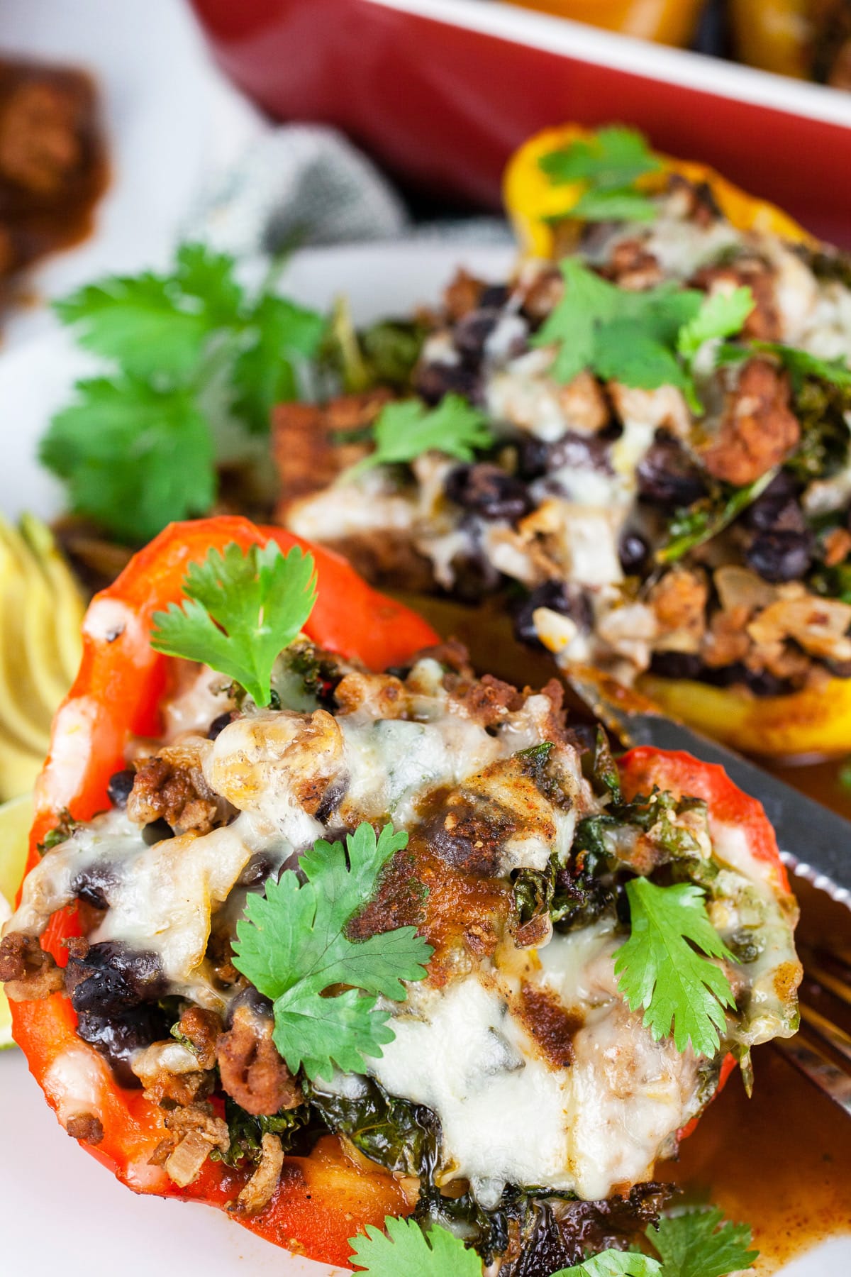 Southwest turkey stuffed peppers with cheese, cilantro, and avocado on white plate.