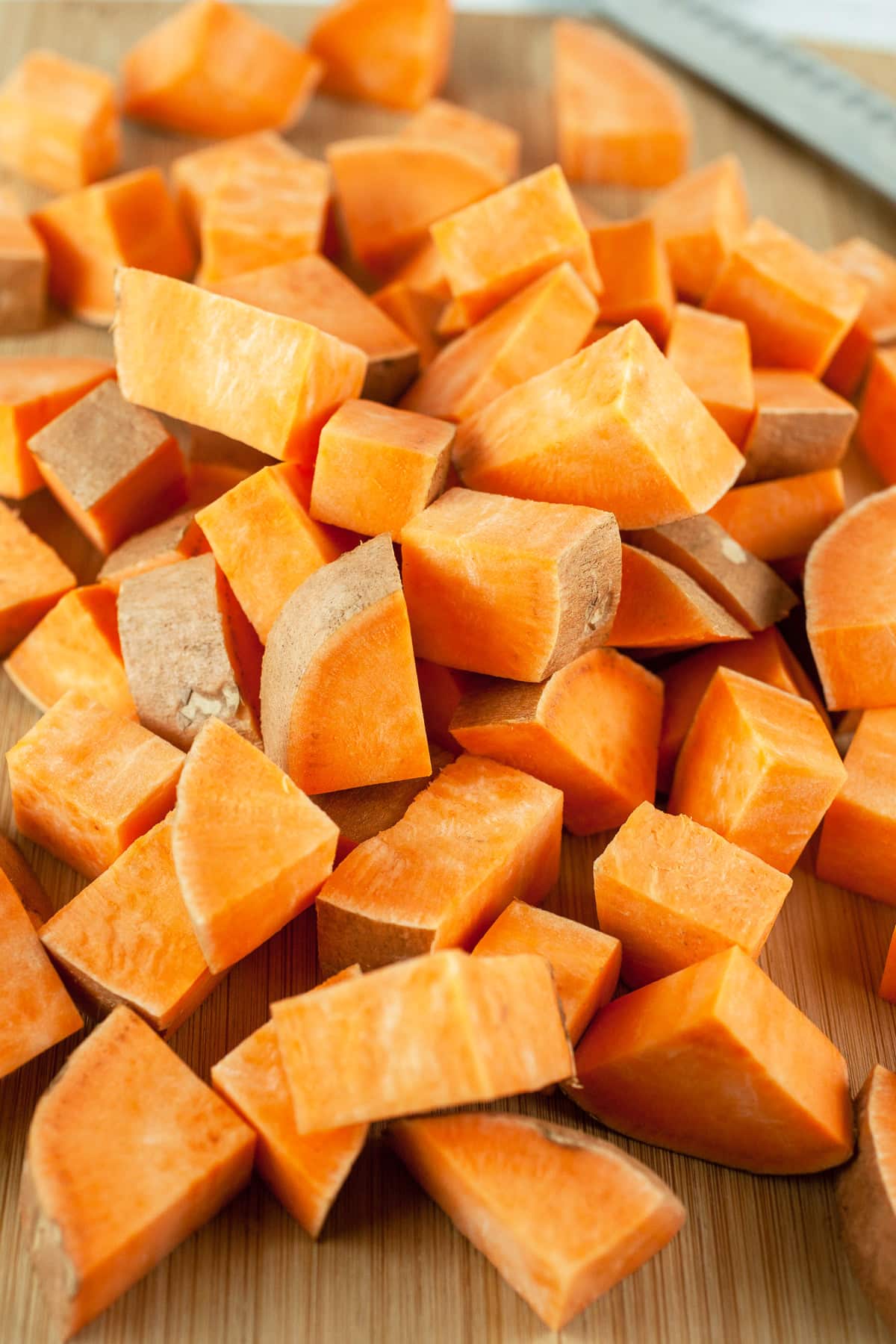 Diced sweet potatoes on wooden cutting board.