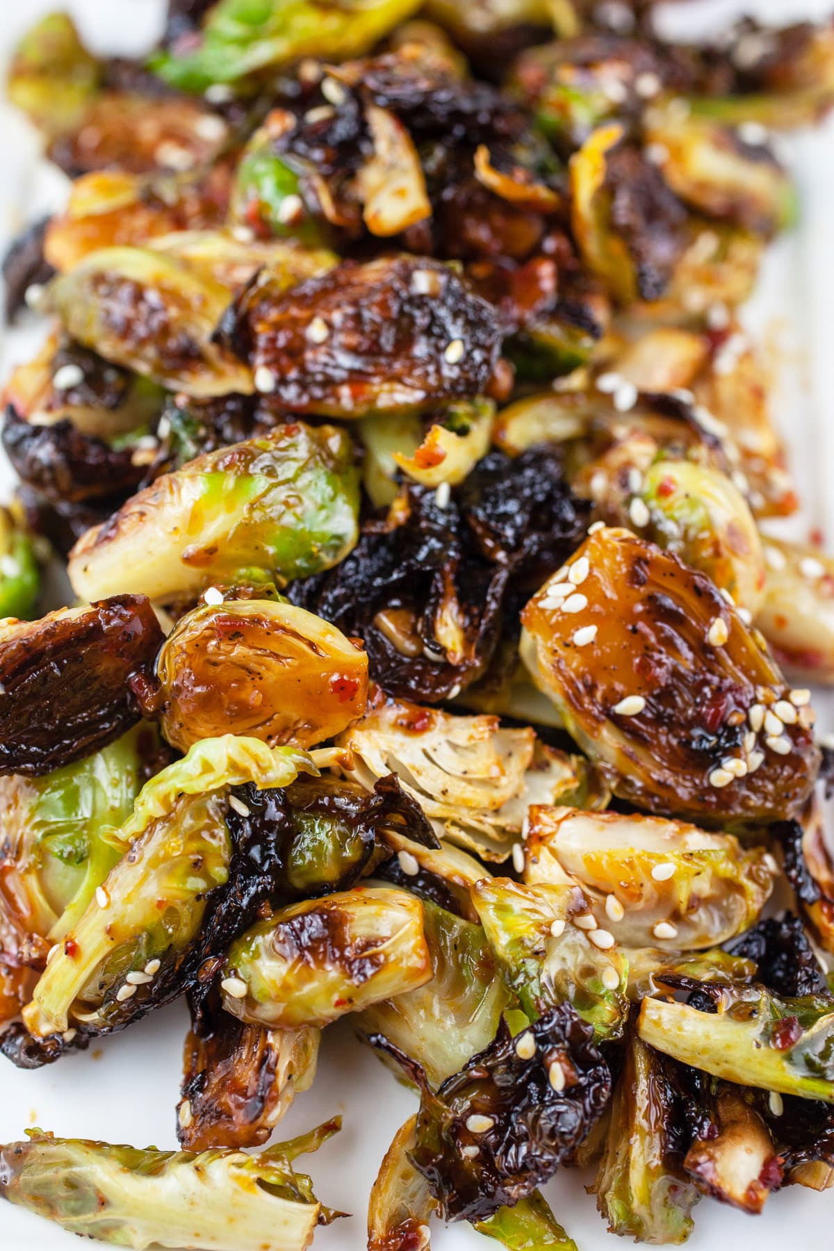 Asian roasted Brussels sprouts with sesame seeds on white platter.