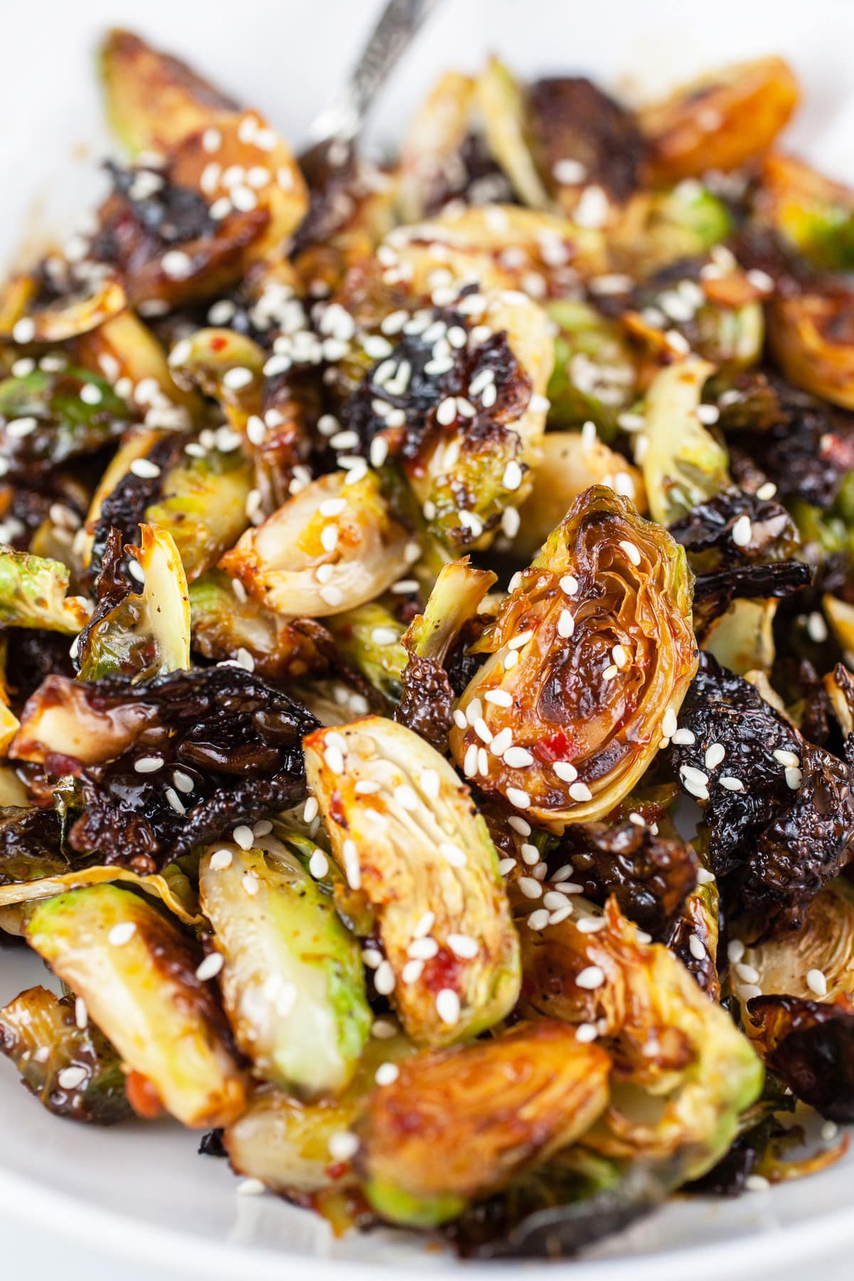 Sweet spicy roasted Brussels sprouts with sesame seeds in white bowl.
