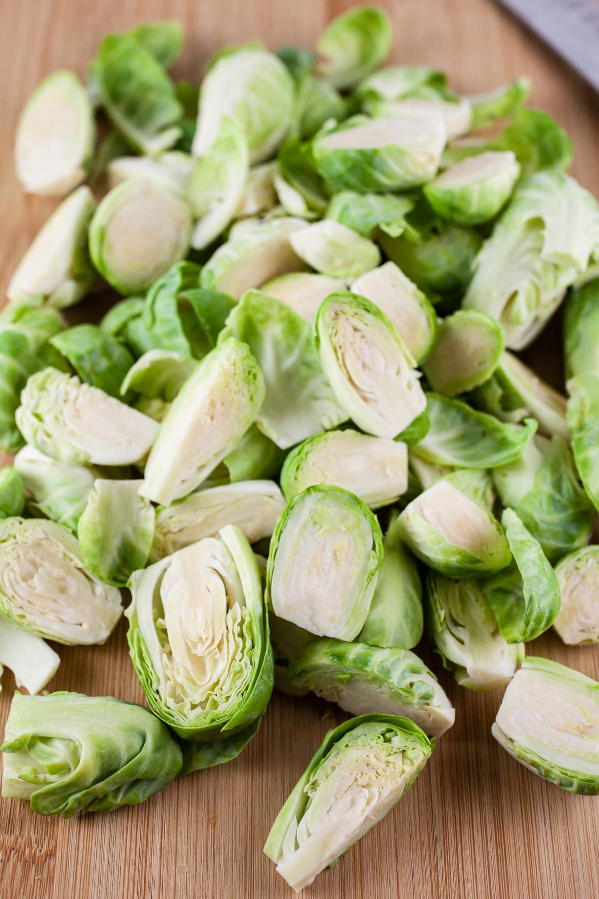 Chopped and trimmed Brussels sprouts on wooden cutting board.