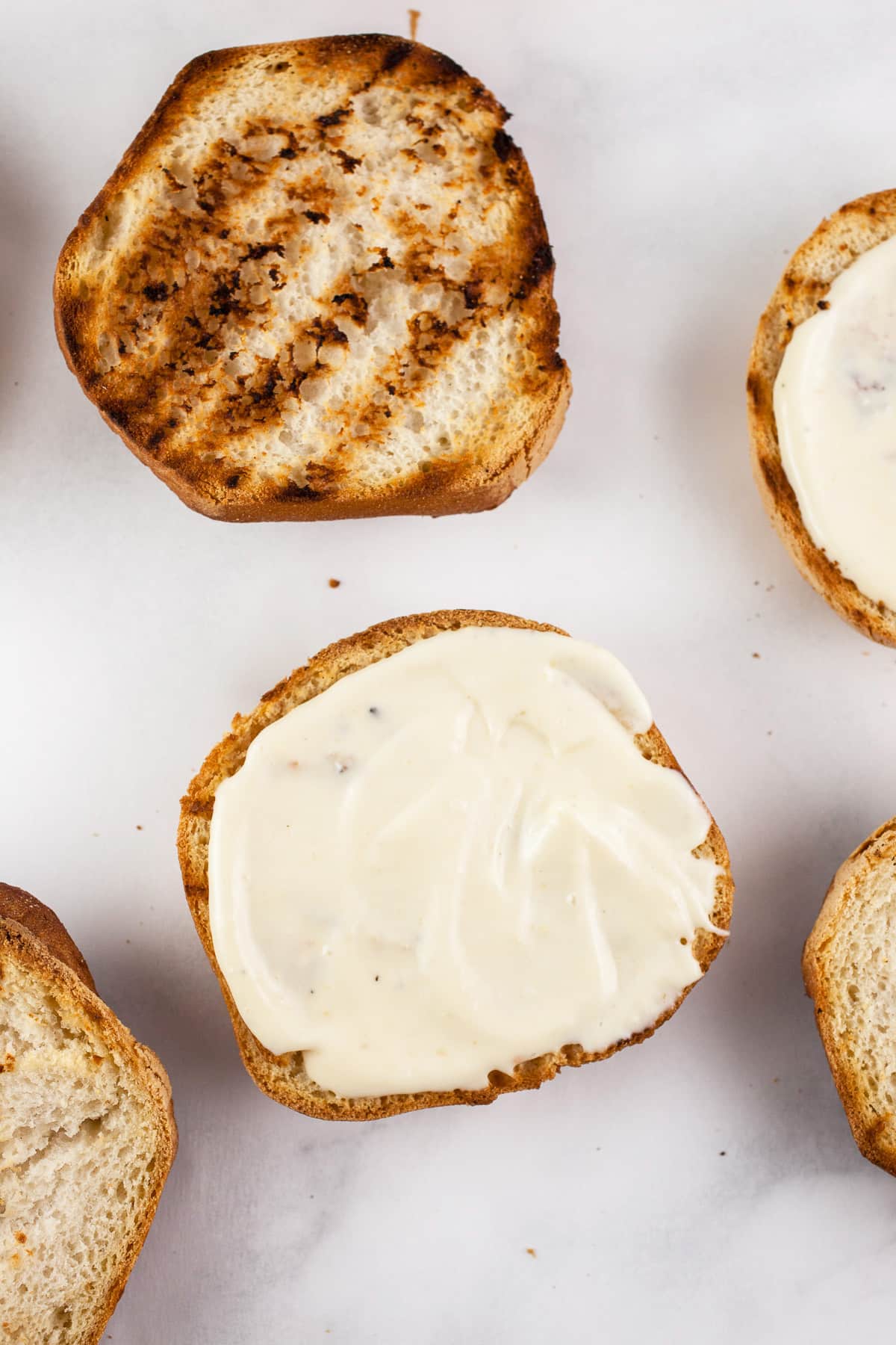 Toasted buns with miso mayo on white surface.
