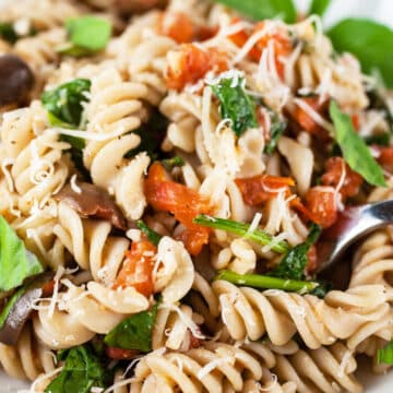 Vegetarian Mediterranean pasta with fresh basil in bowl.