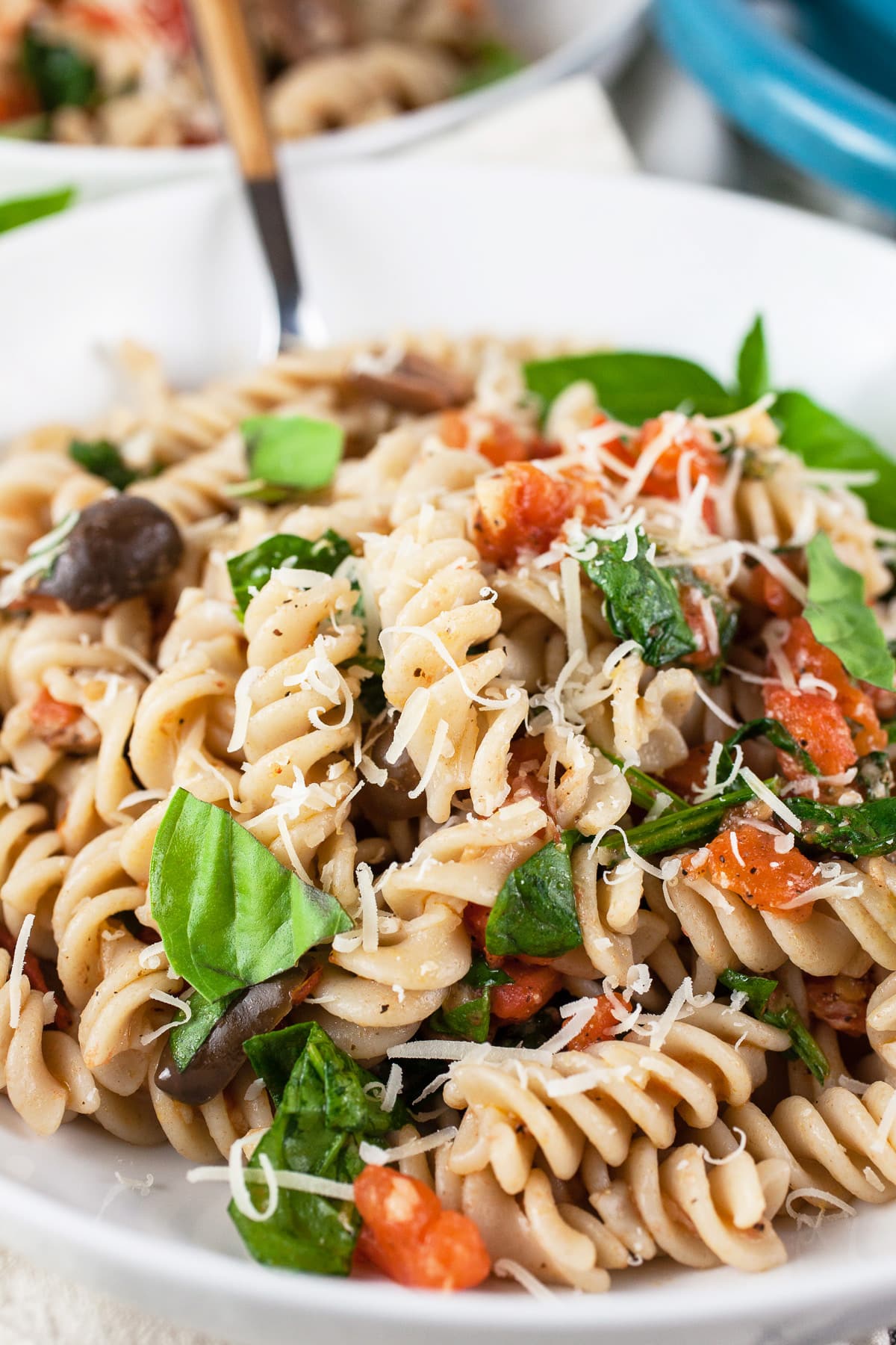 Mediterranean vegetarian pasta in white bowl with fork.