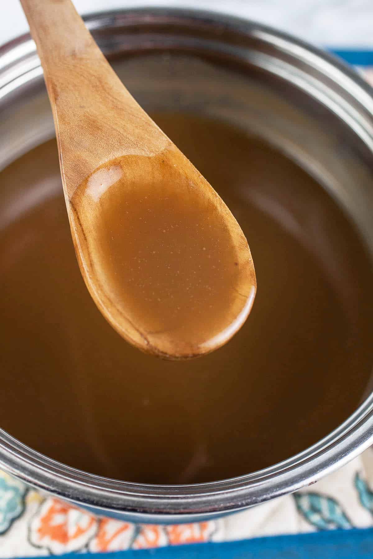 Maple caramel sauce lifted from sauce pan on wooden spoon.