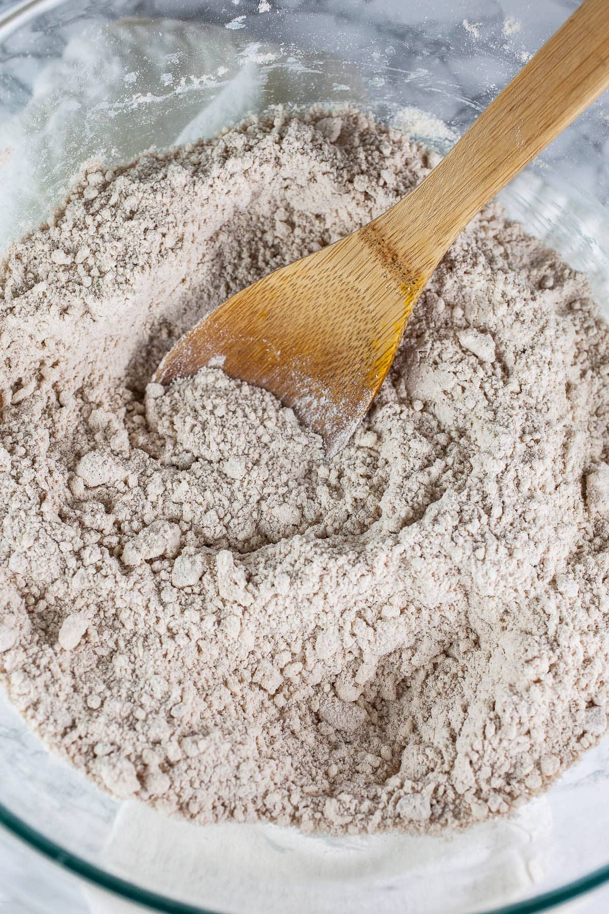 Grated butter incorporated into dry scone ingredients in large glass bowl.