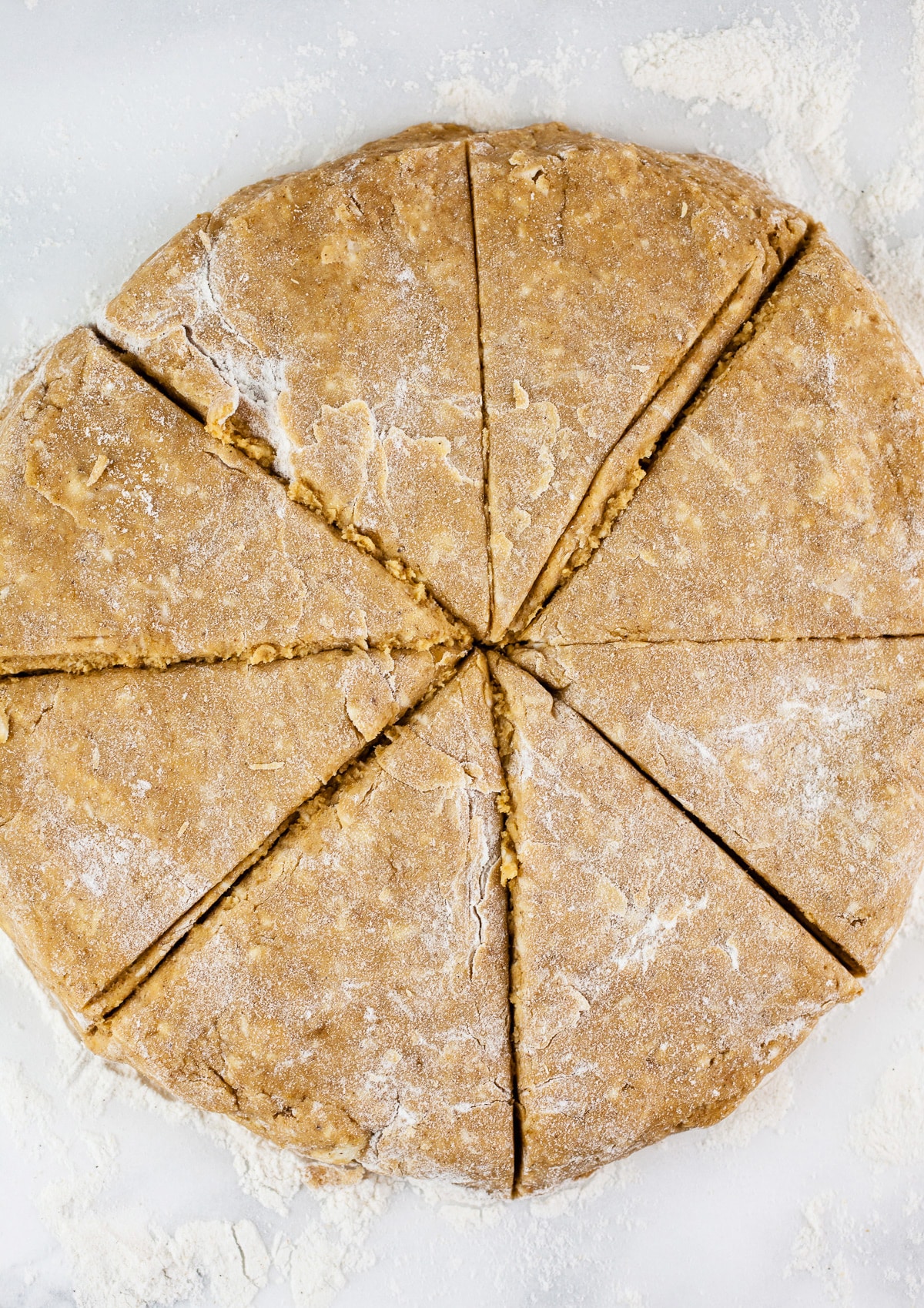 Disc of pumpkin scone dough cut into wedges.