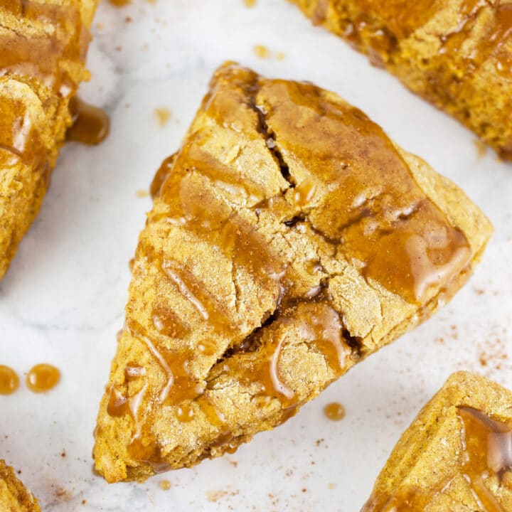 Pumpkin scones with maple glaze on white surface.