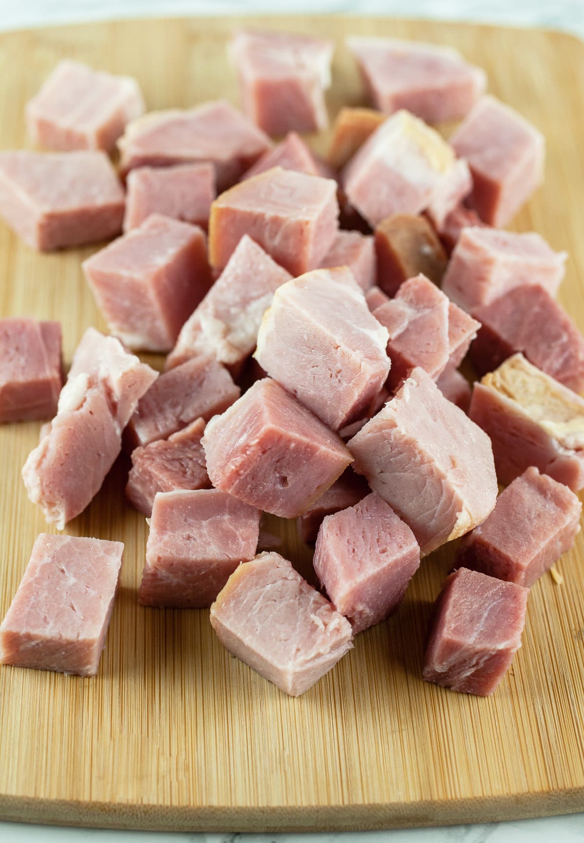 Chopped ham on wooden cutting board.