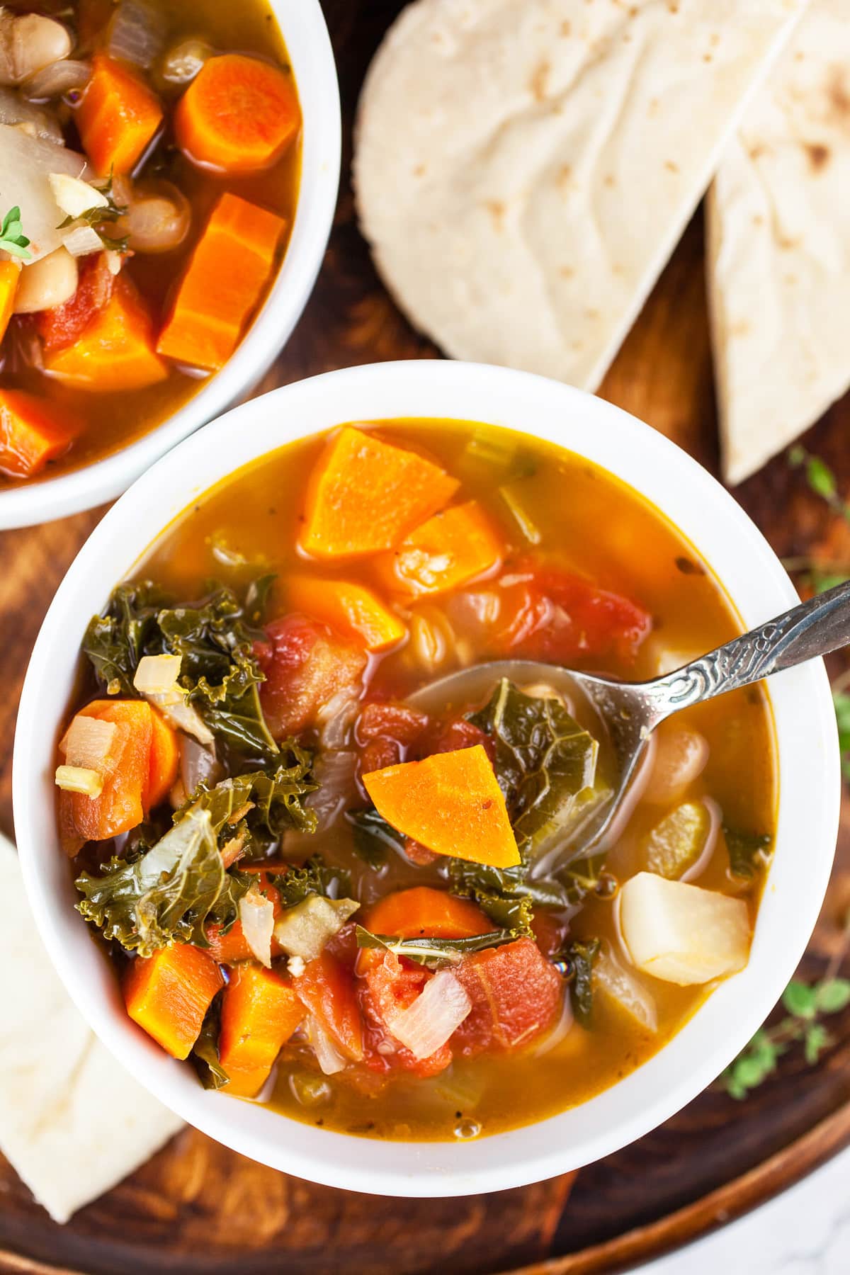 Harvest vegetable soup with sliced pita bread on wooden tray in white bowls.