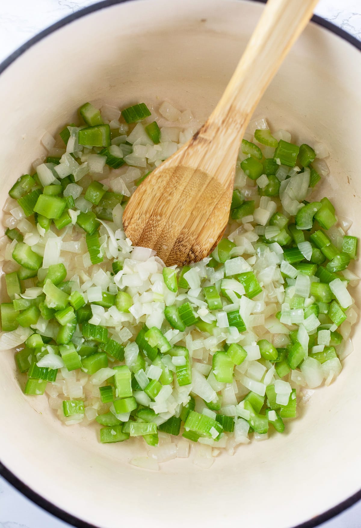 Minced garlic, onions, and celery sautéed in Dutch oven with wooden spoon.