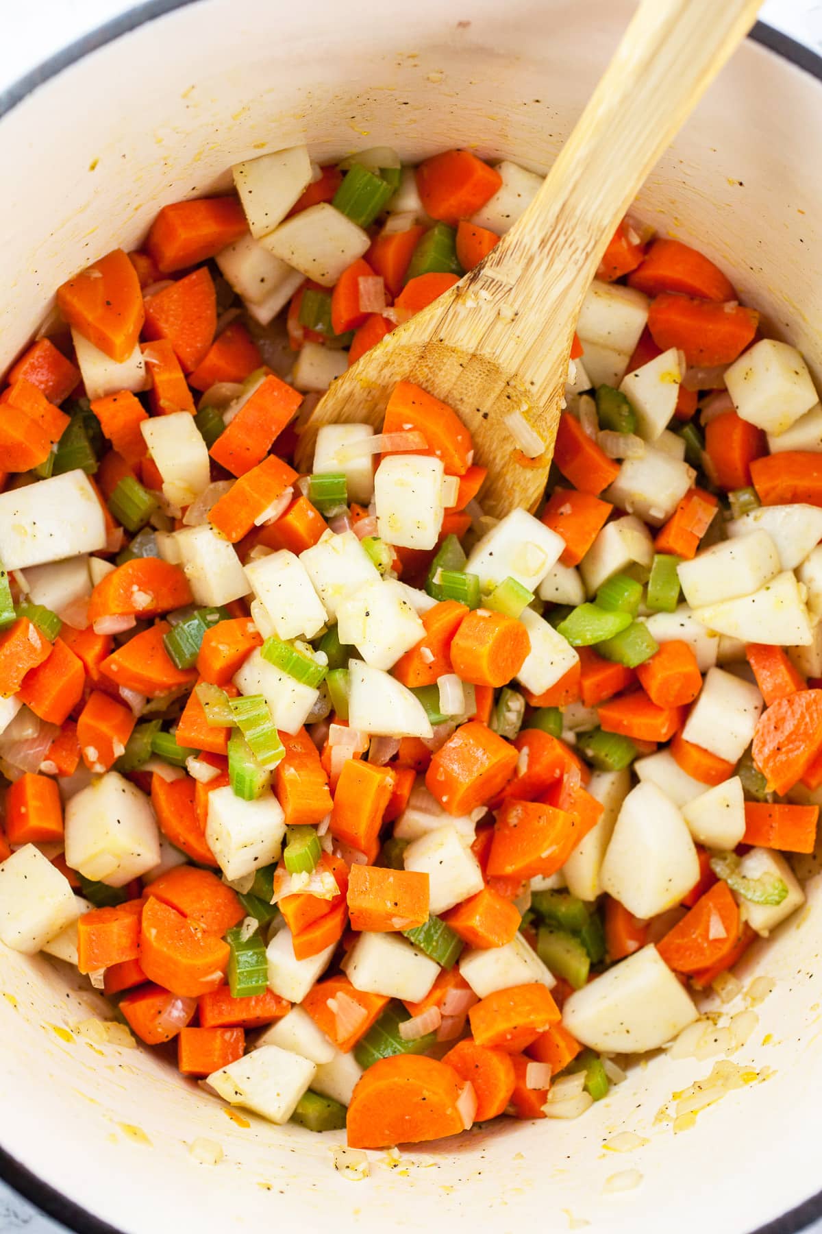 Garlic, onions, celery, carrots, and turnips sautéed in Dutch oven with wooden spoon.