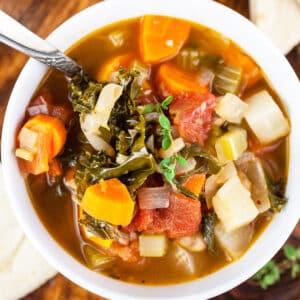 Harvest vegetable soup with pita bread in white bowl.