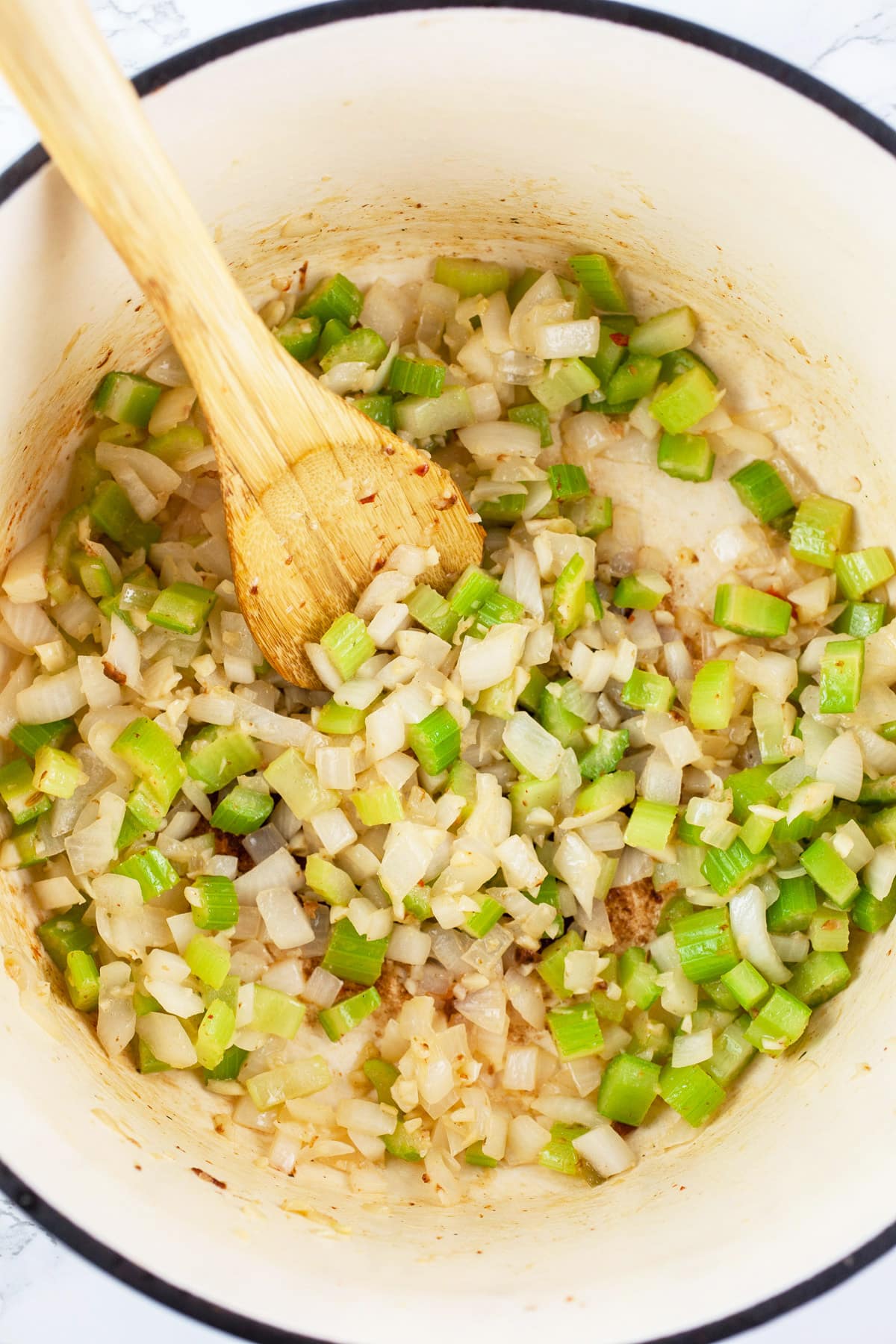 Minced garlic, onions, and celery sautéed in Dutch oven with wooden spoon.