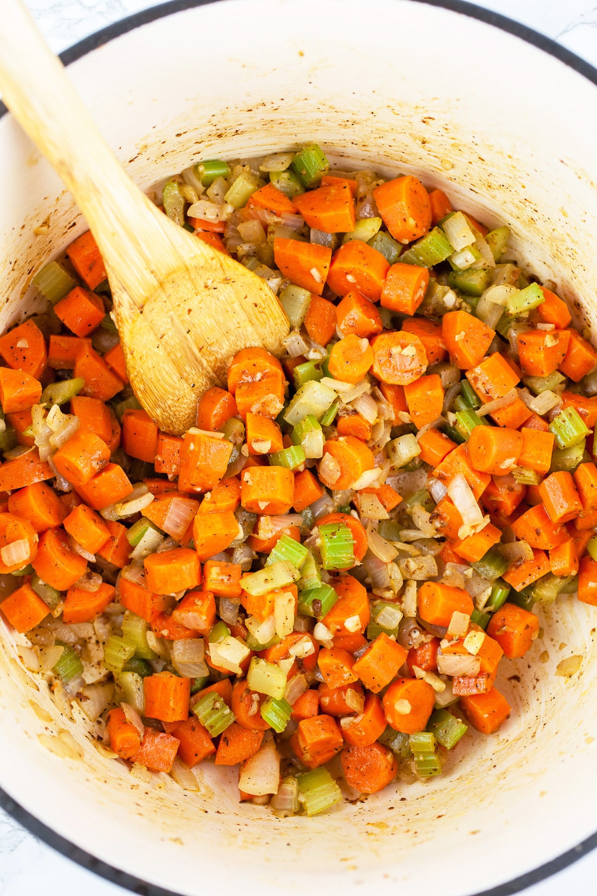 Garlic, onions, celery, and carrots sautéed in Dutch oven with wooden spoon.