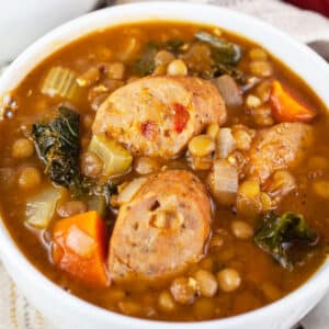 Sausage lentil kale soup in white bowl.