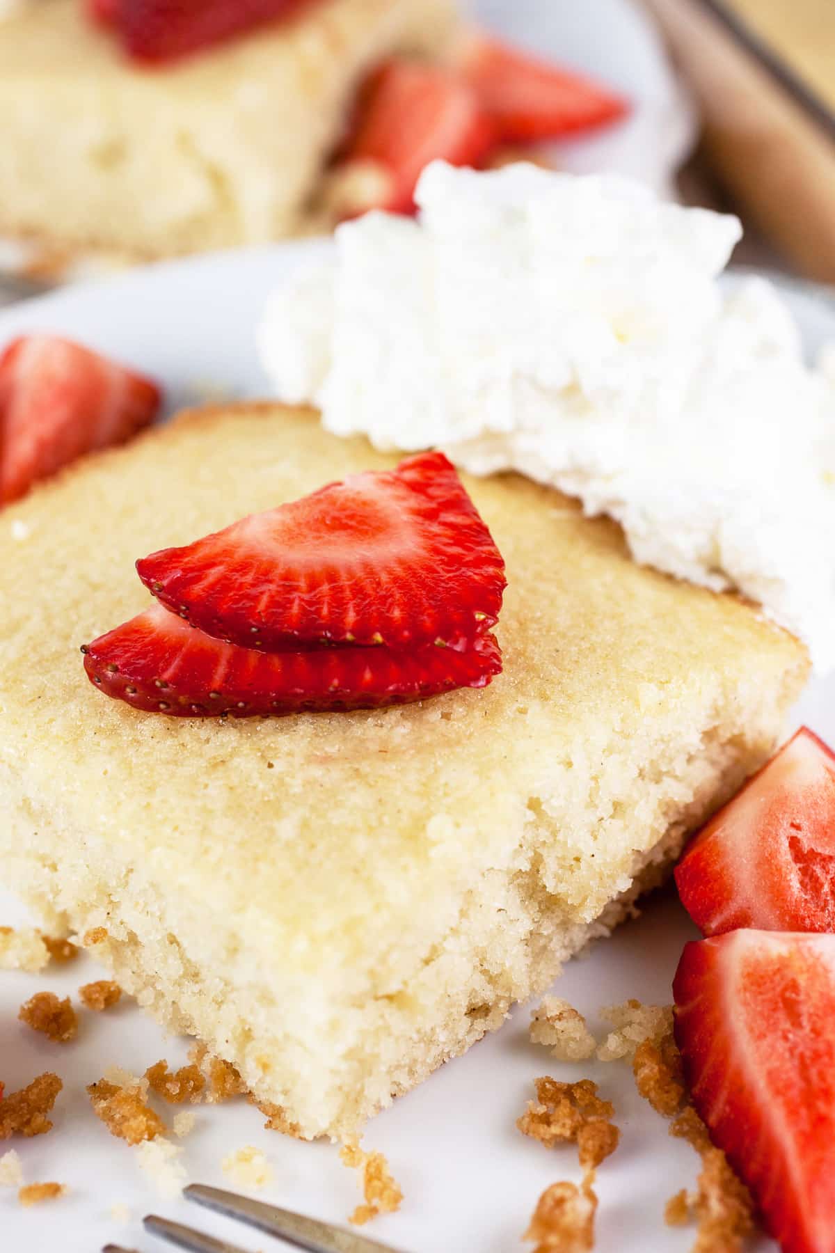 Scandinavian almond cake with strawberries and whipped cream on white plates.