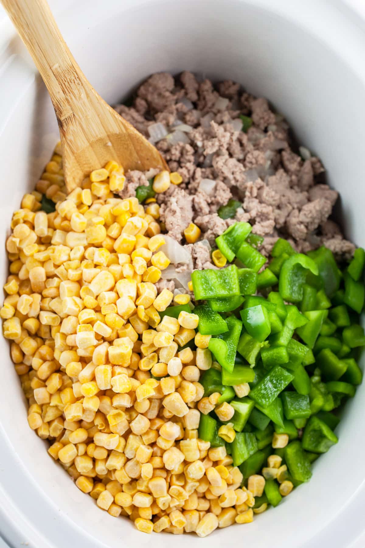 Cooked ground turkey, frozen corn, and diced green bell peppers in slow cooker.