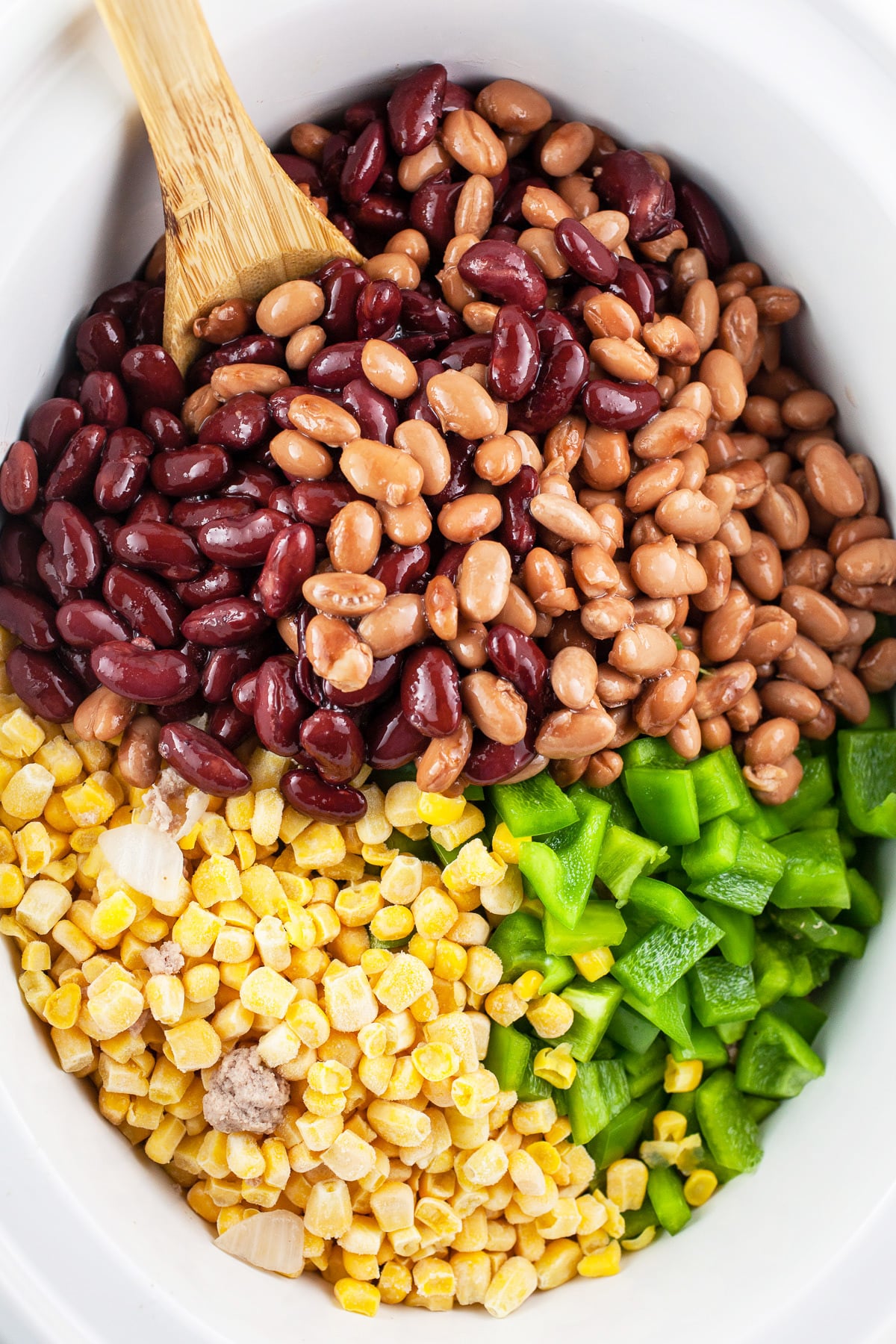 Cooked ground turkey, frozen corn, diced green bell peppers, kidney, and pinto beans in slow cooker.