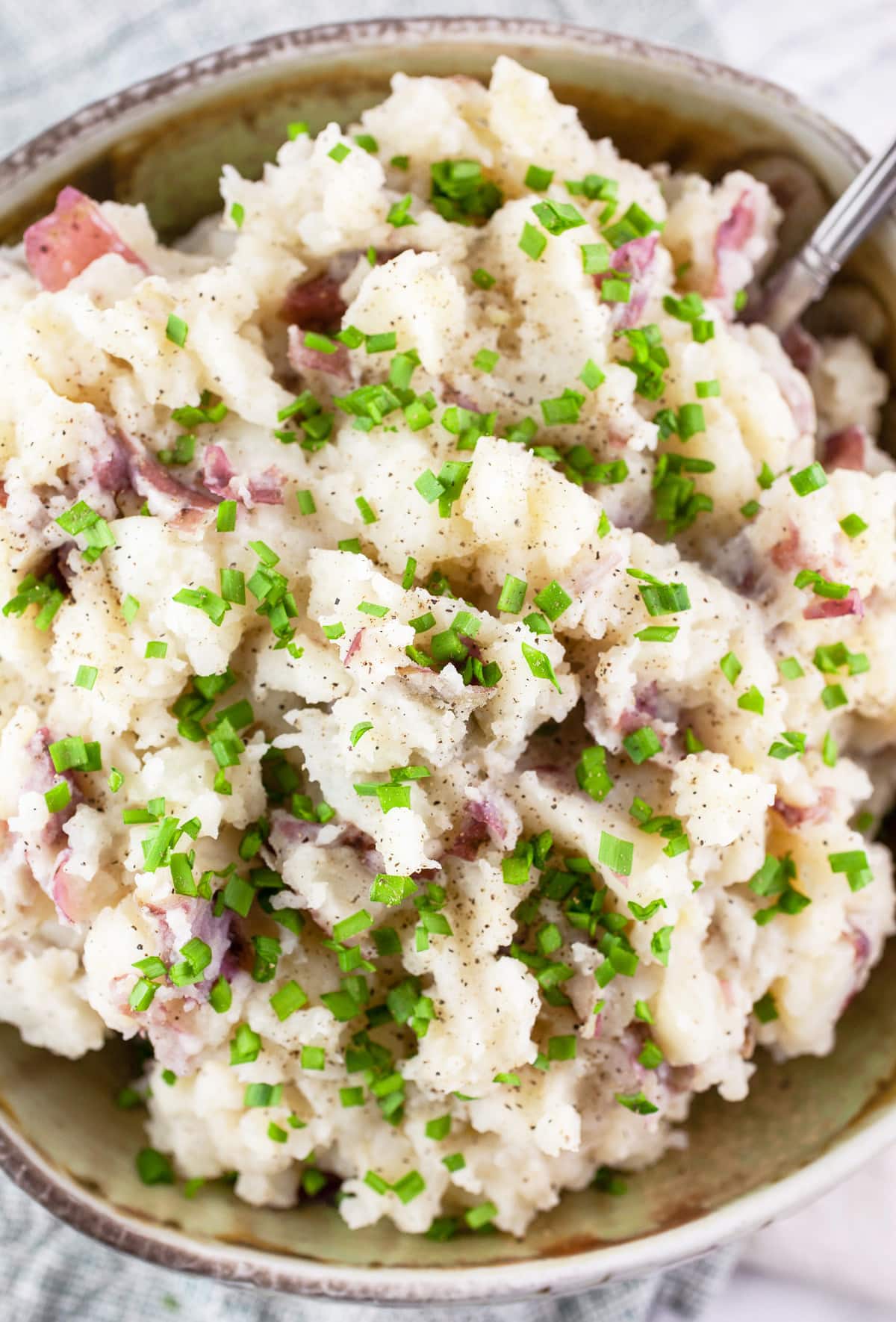 Buttermilk mashed potatoes in ceramic bowl with minced chives.