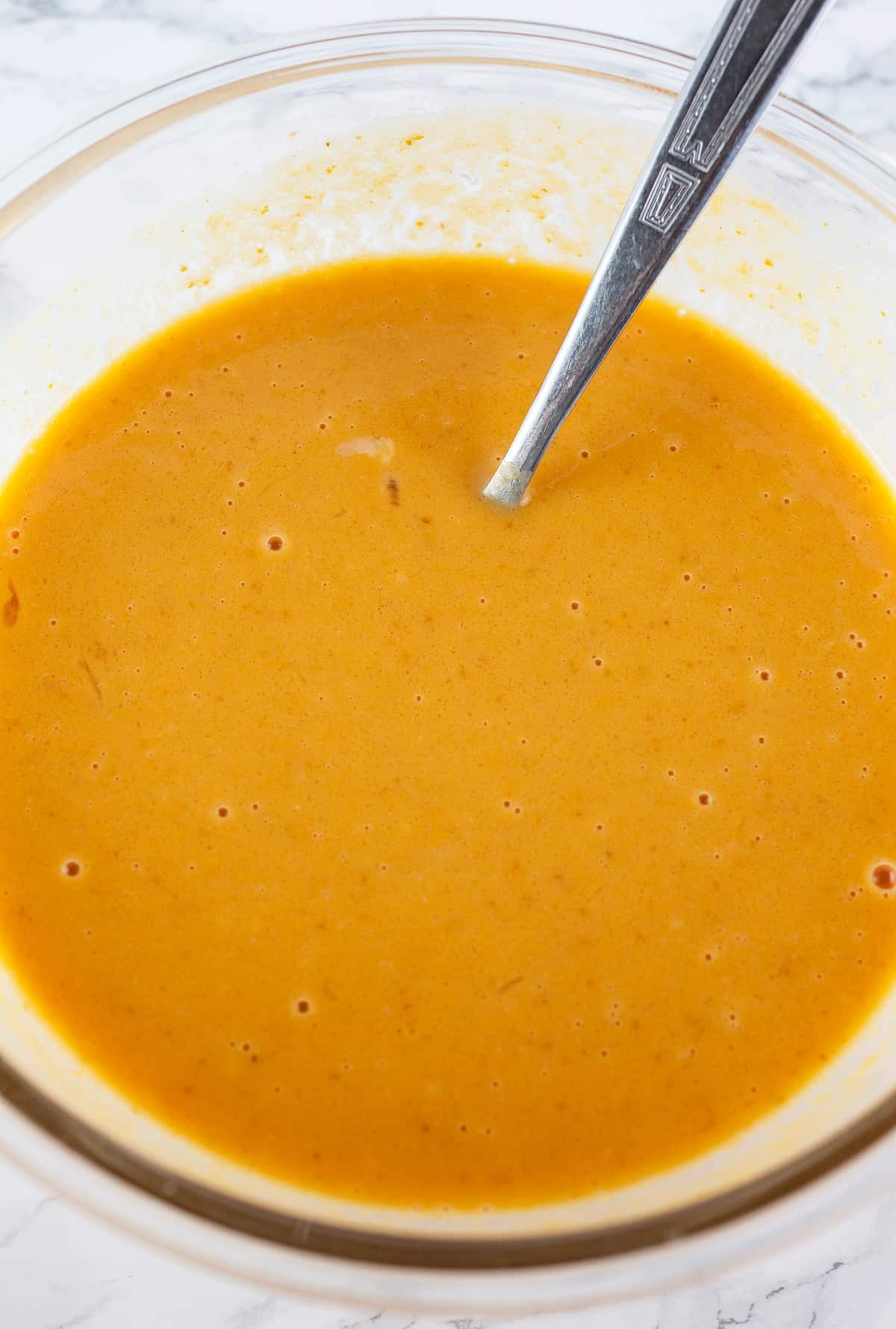 Wet ingredients combined in glass bowl with fork.