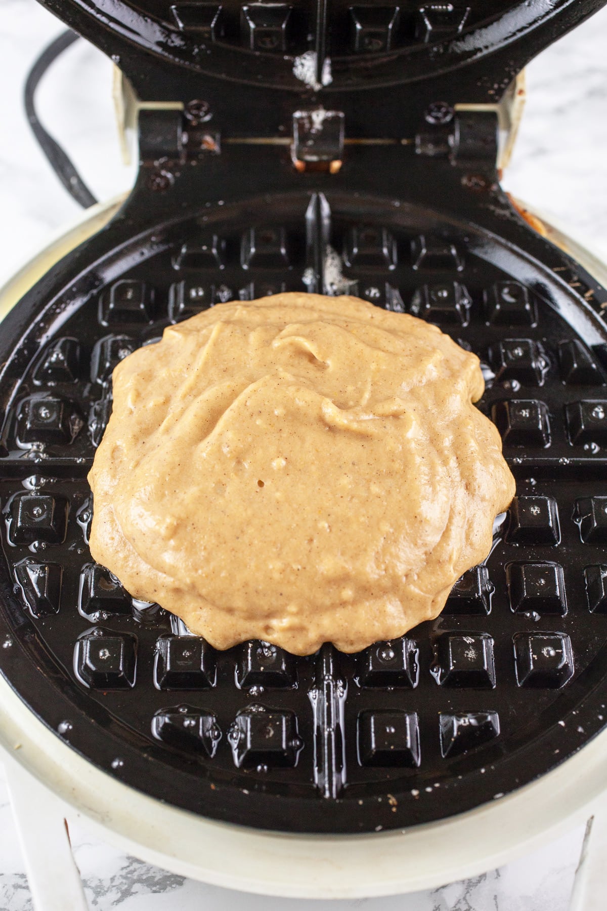 Pumpkin waffle batter in waffle maker.