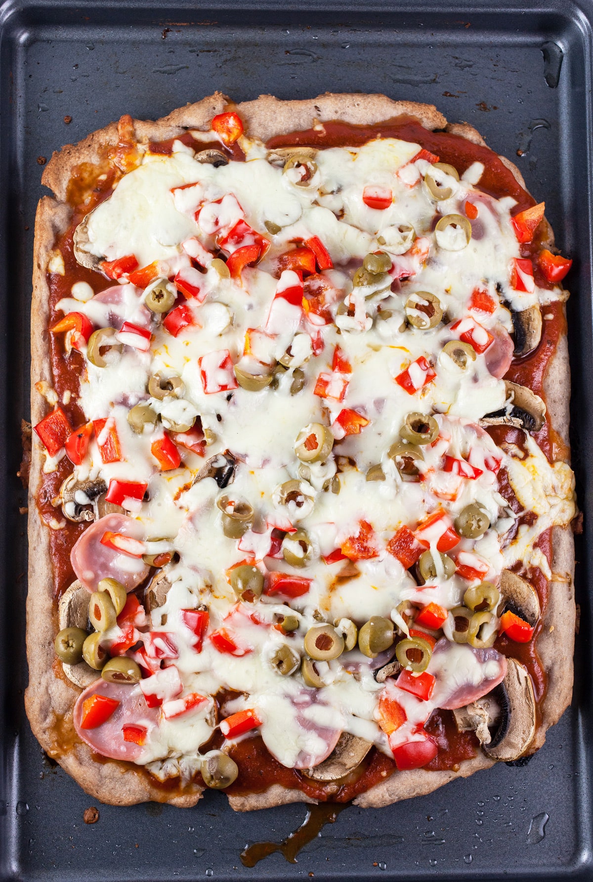 Baked Canadian bacon pizza on baking sheet.