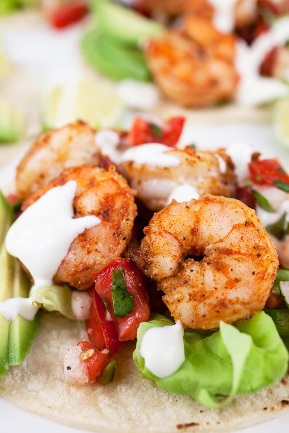 Shrimp tacos with toppings and Mexican crema on corn tortillas.