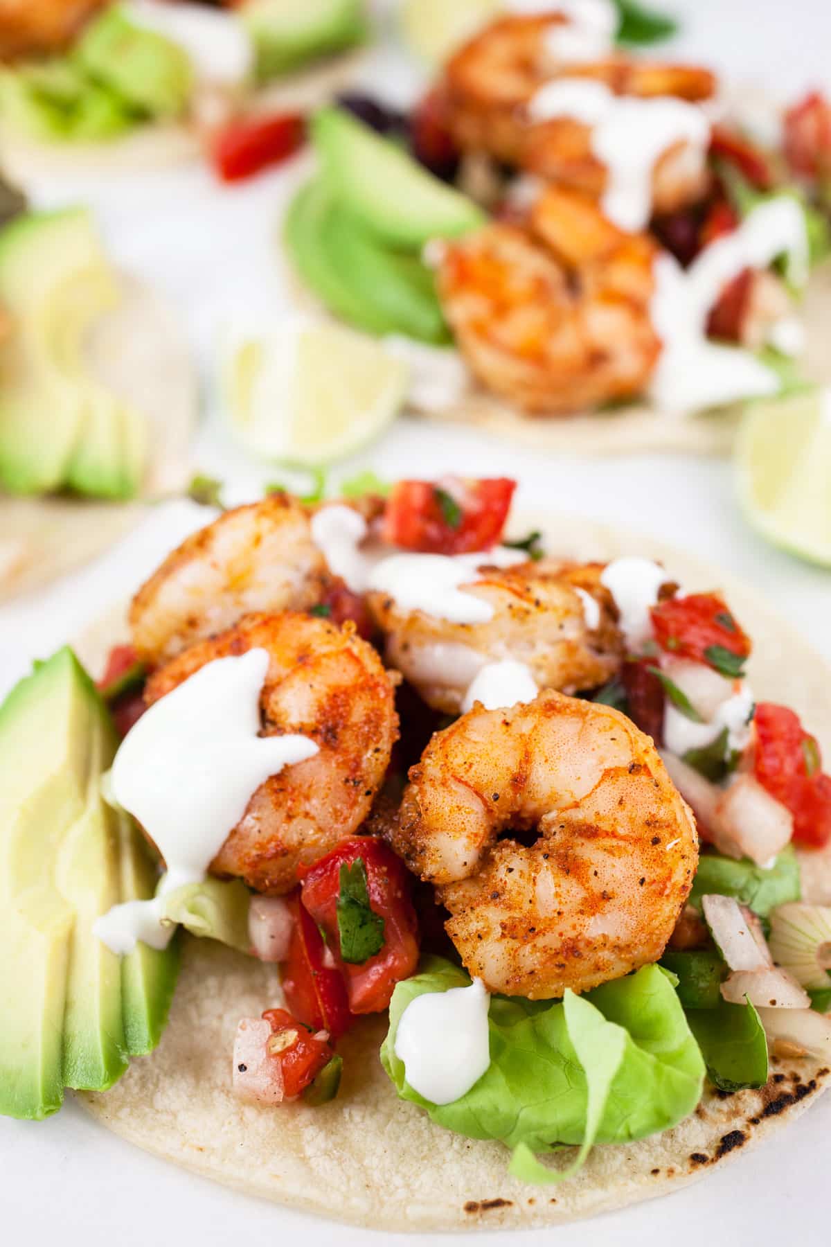 Sheet pan shrimp tacos with toppings and lime crema on corn tortillas.