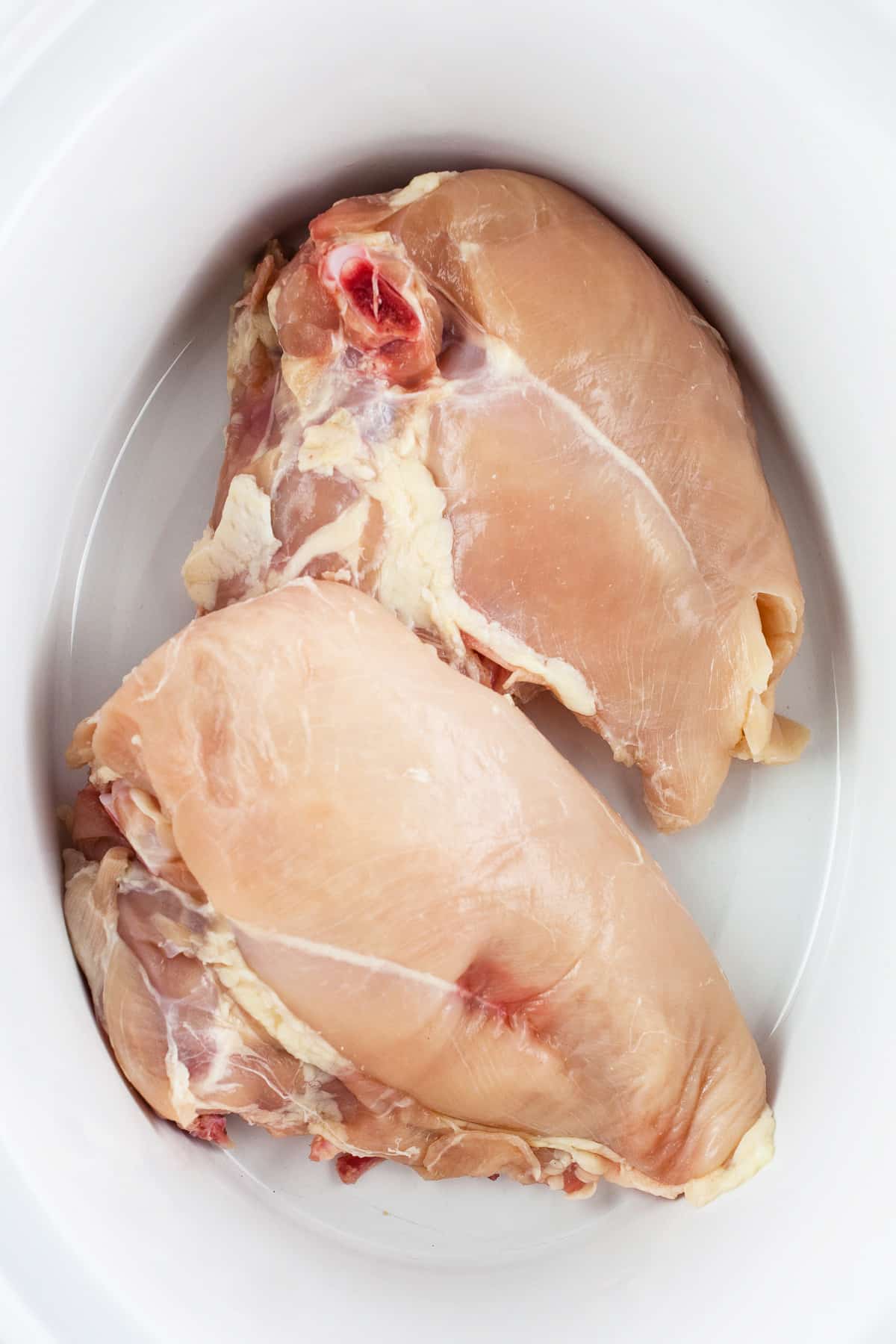 Uncooked split chicken breasts in slow cooker.