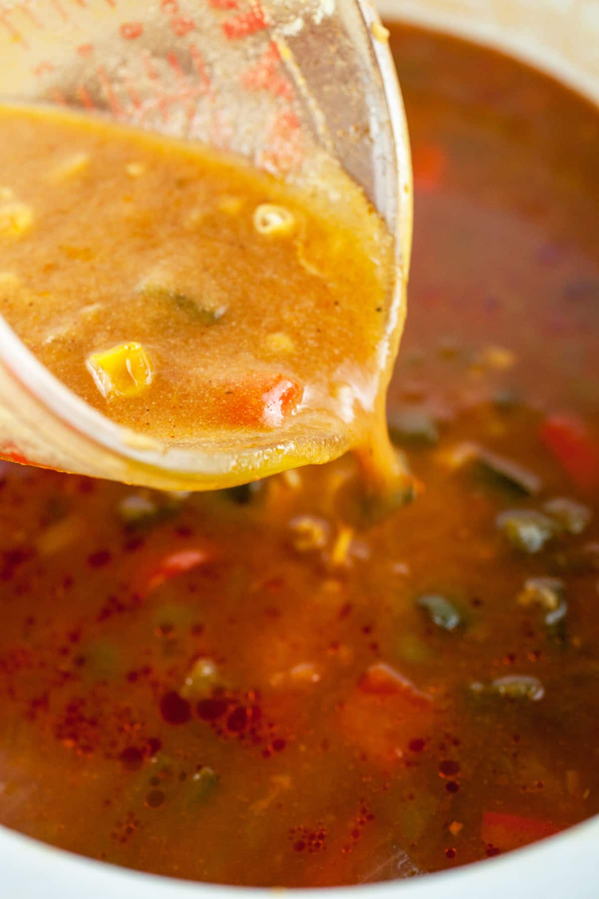 Corn masa slurry poured into slow cooker with glass measuring cup.