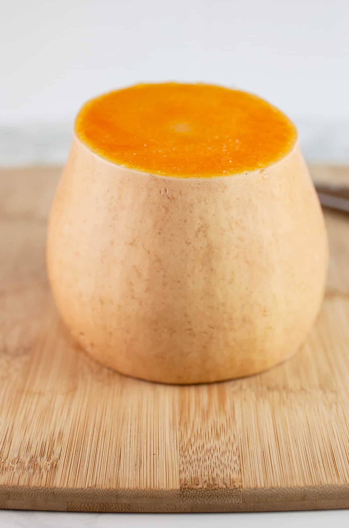 Butternut squash cut in half on wooden cutting board.