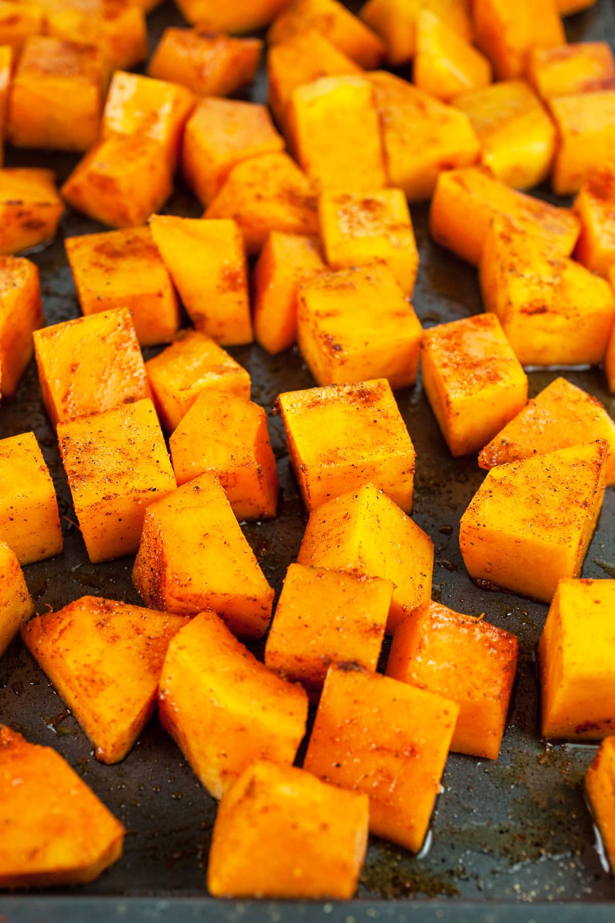 Uncooked spiced butternut squash cubes on baking sheet.