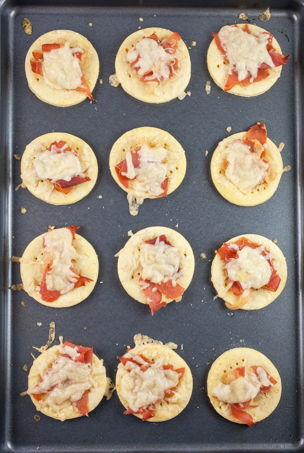 Gruyere prosciutto tartlets on baking sheet.