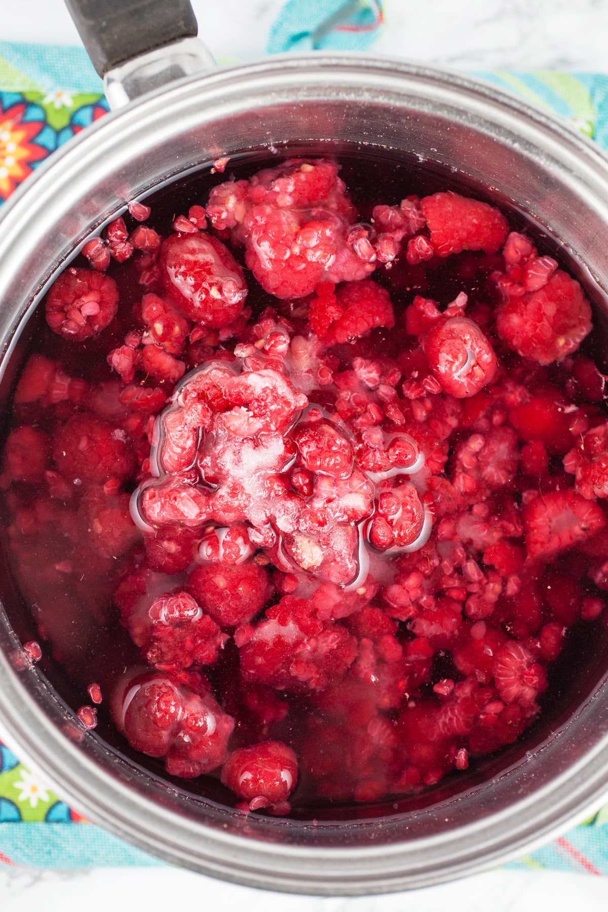 Frozen raspberries, sugar, and water in sauce pan.