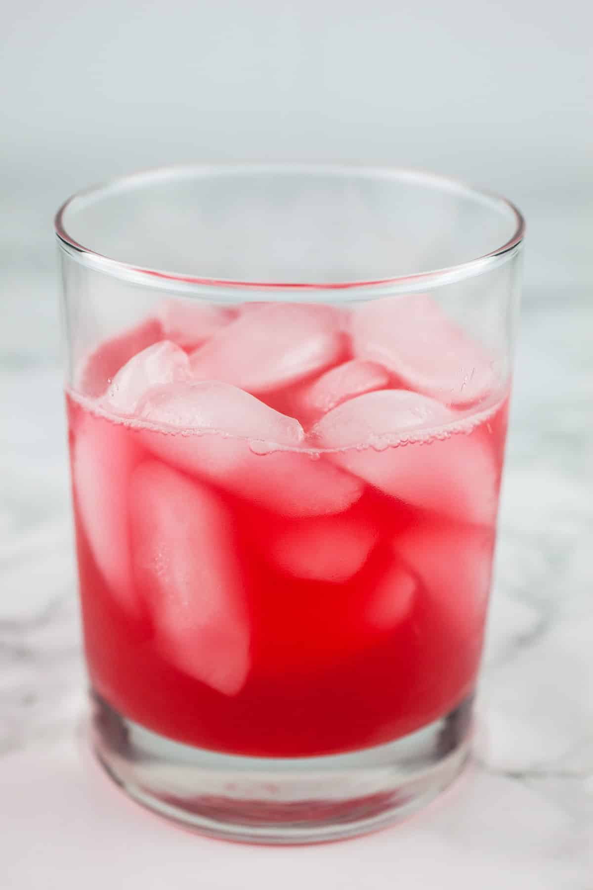 Raspberry syrup, vodka, and lime juice in lowball glass with ice.
