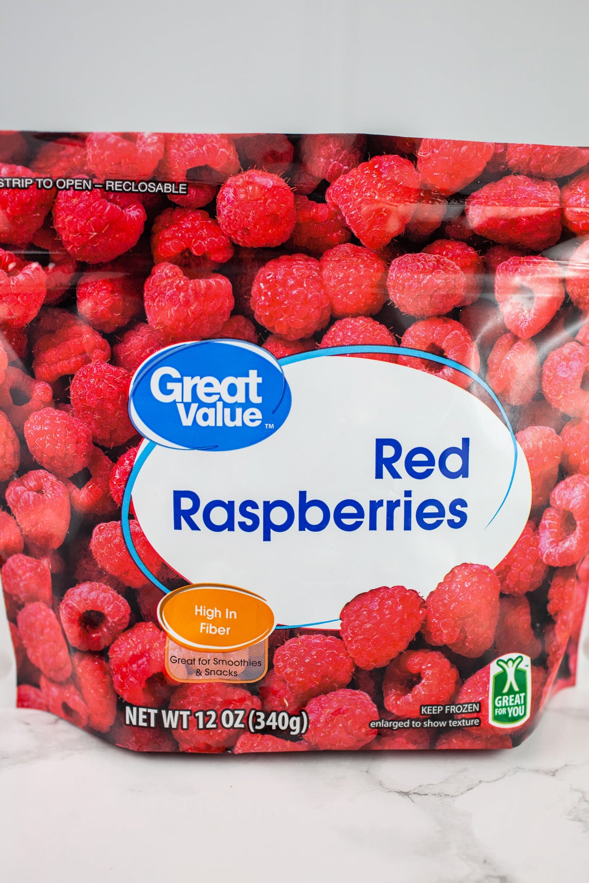 Bag of frozen raspberries on white surface.
